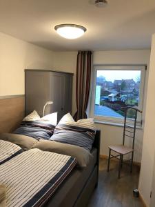 a bedroom with two beds and a chair and a window at Ein kleines Haus in Fehmarn