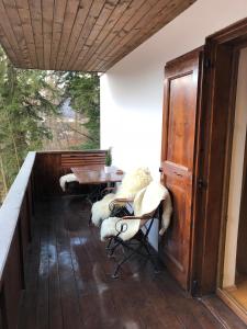 a porch with chairs and tables on a wooden floor at STILL Apartament Sinaia in Sinaia