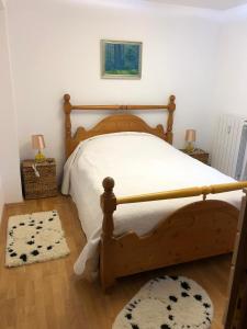 a bedroom with a wooden bed with white sheets and a rug at STILL Apartament Sinaia in Sinaia