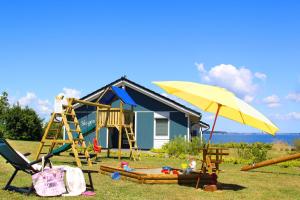 una casa azul con parque infantil y sombrilla amarilla en Ferienhaus Skagen, en Steinbergkirche 11 fotos más