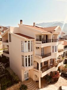 a white apartment building with balconies in front of the ocean at Apartments Grabovica in Bar