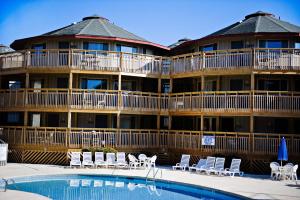 a large hotel with a swimming pool and chairs at Outer Banks Beach Club in Kill Devil Hills