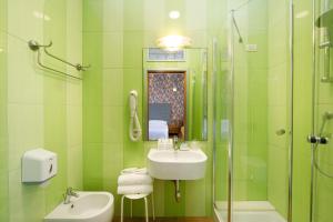 een groene badkamer met een wastafel en een douche bij Hotel Del Corso in Sorrento