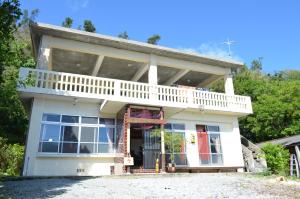 名護市にあるbackpackers guesthouse Borderのバルコニー付きのホワイトハウスです。