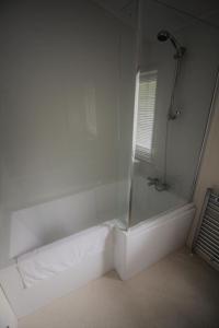 a white bathroom with a shower with a glass door at Bucklegrove Holiday Park in Cheddar
