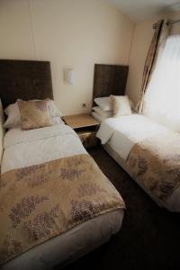 1 dormitorio con 2 camas y ventana en Bucklegrove Holiday Park, en Cheddar