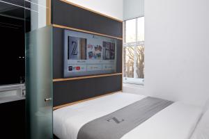 Un dormitorio con una cama con un televisor en la pared. en The Z Hotel Covent Garden, en Londres