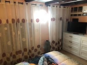 1 dormitorio con 1 cama, TV y cortinas en Locanda Beatrice, en San Remo