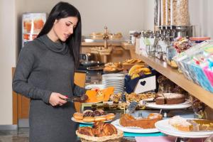 Una donna in piedi davanti a un tavolo di cibo di City Hotel & Suites a Foligno