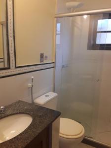 a bathroom with a shower and a toilet and a sink at Pousada Casa das Rosas in Búzios