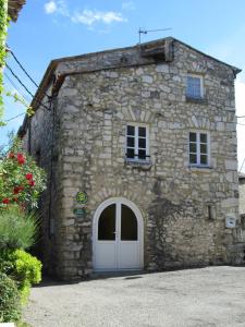 un antiguo edificio de piedra con una puerta blanca en Gîte Les Remparts, en La Garde-Adhémar