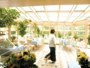 une personne se promenant dans une véranda avec des tables et des chaises dans l'établissement Hotel Stegner, à Rödelsee