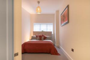 a bedroom with a bed with a red blanket at Cathedral View - An Exclusive Private Apartment on Cathedral Green, Exeter in Exeter