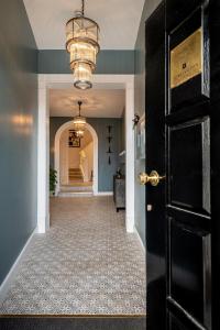 a hallway with a black door and a chandelier at Cathedral View - An Exclusive Private Apartment on Cathedral Green, Exeter in Exeter