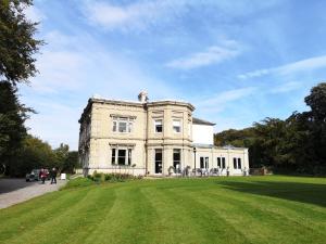 a large white house with a grass field in front at Cleatham Hall in Manton