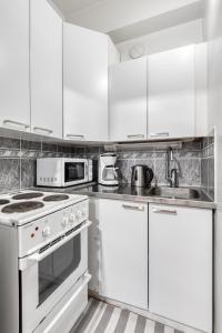 a white kitchen with white cabinets and a sink at Apartments Borg in Pori
