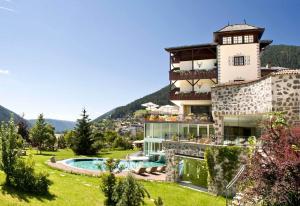 a building with a pool and a resort at Romantik Hotel Post in Nova Levante