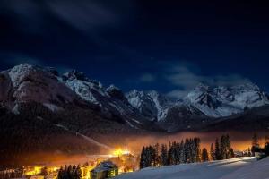 a snow covered mountain range at night with a town at Appartamenti Annarita in Sappada