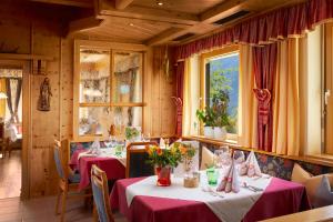 restauracja z dwoma stołami z czerwonymi obrusami w obiekcie Hotel Gasthof Abelhof w mieście Neukirchen am Großvenediger