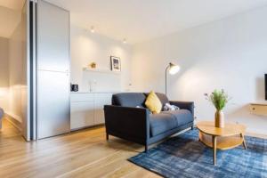 a living room with a blue couch and a table at Joie Paris Porte Maillot - Palais Des Congrès in Neuilly-sur-Seine