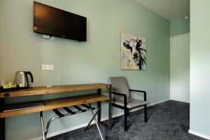 a room with a desk and a television on a wall at Slaap bij TRIX in Arnhem