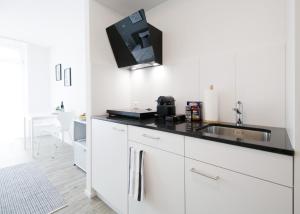 a kitchen with a sink and a tv on the wall at VARIAS Lifestyle Apartments in Elsau