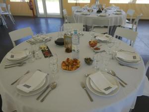 a white table with plates and glasses and food on it at Quinta da Retorta in Pinhel