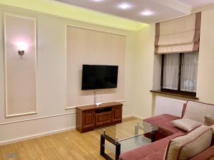 a living room with a tv and a couch and a table at Two-bedroom on Lesi Ukrainky in Lviv