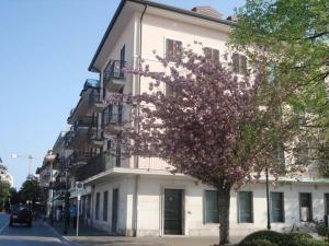 un edificio blanco con un árbol florido delante de él en Riviera Appartament, en Grado