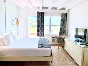 een slaapkamer met een bed, een bureau en een televisie bij Broadmore Miami Beach in Miami Beach