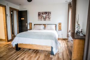 a bedroom with a bed and a dresser at Gîte du Haut des Arbres in Saguenay