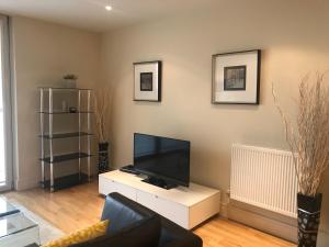 a living room with a flat screen tv on a white cabinet at Canary Wharf Serviced Apartments in London