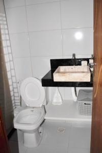 a bathroom with a white toilet and a sink at Costa Bella Residence in Conde