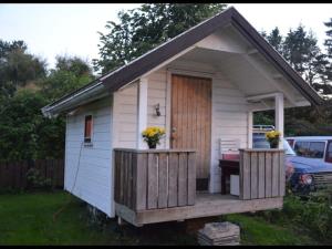 um pequeno barracão branco com um alpendre e uma porta em Your cabin in Trondheim em Tiller