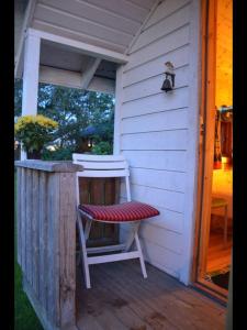 uma casa branca com um banco e uma cadeira num alpendre em Your cabin in Trondheim em Tiller