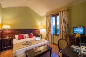 a bedroom with a bed and a desk and a television at Country Hotel & Resort I Calanchi in Ripatransone