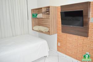 蒙蒂斯克拉魯斯的住宿－Hotel e Restaurante Residencial，一间卧室设有床铺、电视和砖墙