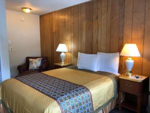 a hotel room with a bed and a chair and lamps at Cedar Inn & Suites in South Lake Tahoe