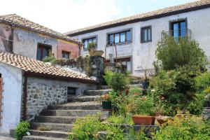 una vecchia casa in pietra con scale in un villaggio di La Pietra Antica O' Munti a Puntalazzo