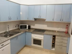 a kitchen with white cabinets and a sink and a microwave at THE 69 in Puerto Rico de Gran Canaria