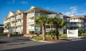 a large apartment building with palm trees in front of it at Caribbean Resort Myrtle Beach in Myrtle Beach