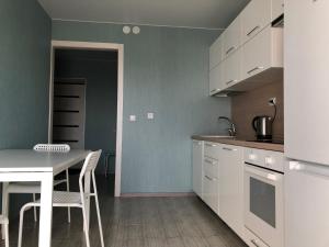 a kitchen with white cabinets and a table and chairs at Парк Университет Exclusive МоМеНтАлЬнОе БЕСКОНТАКТНОЕ ЗАСЕЛЕНИЕ in Vladimir