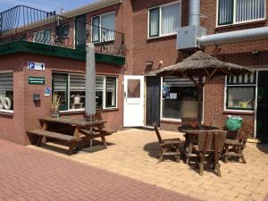 eine Terrasse mit einem Tisch, Stühlen und einem Sonnenschirm in der Unterkunft Hotel-Pension Ouddorp in Ouddorp