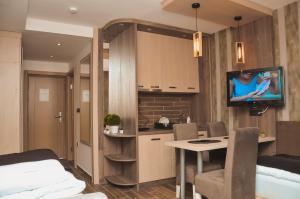 a room with a kitchen and a table with a tv on the wall at Apartman Mitra Angella Konaci in Kopaonik