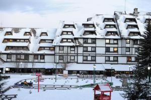 a snow covered building with a courtyard in front of it at Apartman Mitra Angella Konaci in Kopaonik