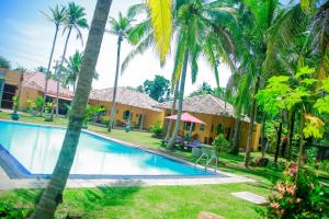 a resort with a swimming pool and palm trees at Kurumba Villas in Bentota