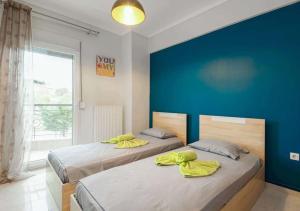 two beds in a bedroom with a blue wall at Socrates & Froso's lovely maisonette in Thessaloniki