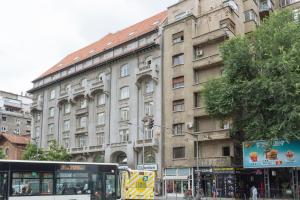 un autobús está estacionado frente a un gran edificio en Petite maison sur le boulevard en Bucarest