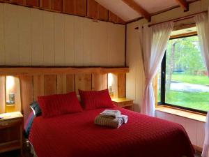 a bedroom with a red bed with a window at Cabañas Peumayén Neltume in Neltume