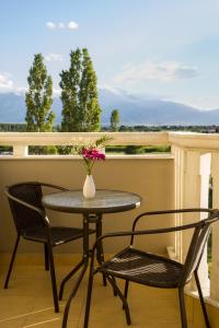 una mesa y 2 sillas y un jarrón con flores en el balcón en Niriides Studios and Apartments, en Paralia Katerinis